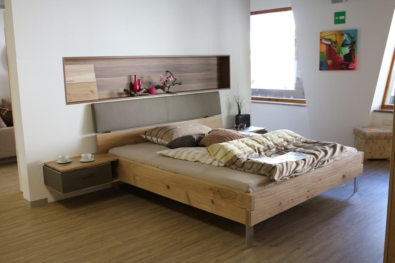szerokie dwuosobowe łóżko przy białej ścianie z pościelą w paski